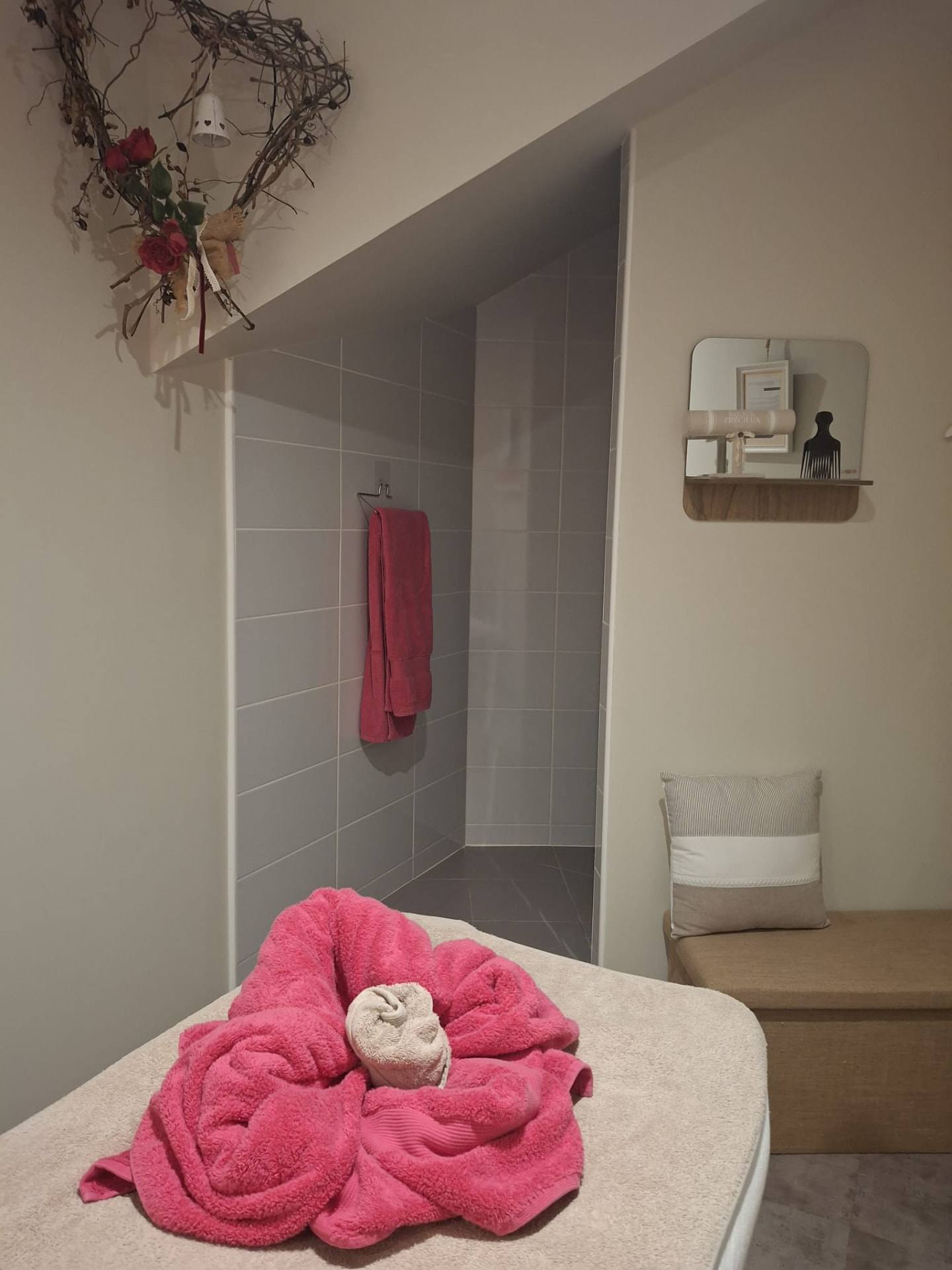 Coin douche de la cabine avec serviette rose pliée en fleur et banc coffre